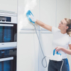 Egy nő gőzöléssel tisztítja a konyhaszekrényt a Livington SteamTouch készülékkel.